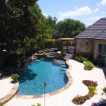 A pool with a large patio area and a swimming pool.