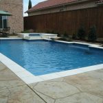 A pool with a stone deck and white trim.