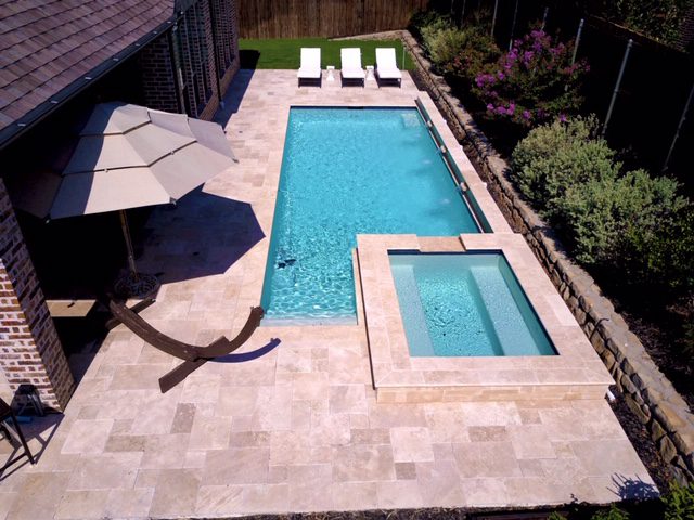 A pool with an umbrella and chairs in the middle of it