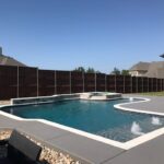 A pool with a stone surround and a concrete deck.