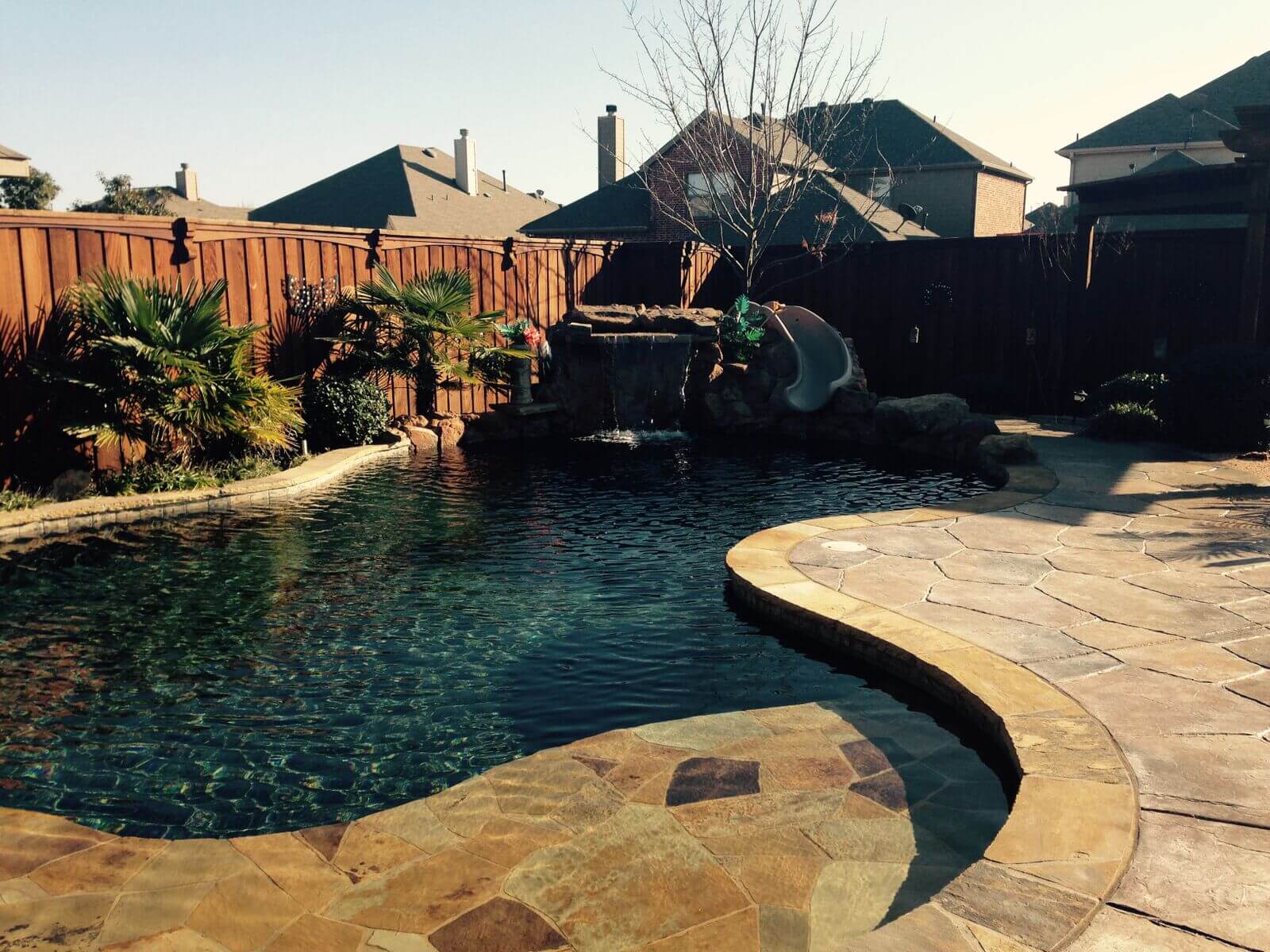 A pool with a stone path and a waterfall.