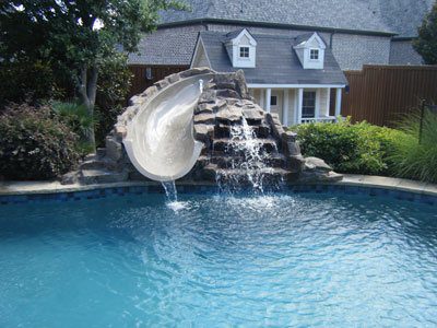 A pool with water slide and waterfall in it